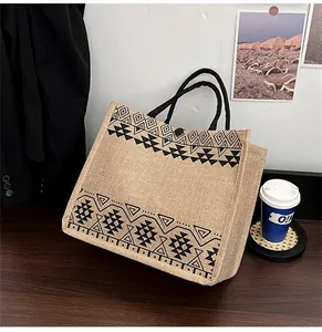 Detail of jute tote bag with black geometric patterns and woven rope handle on wooden desk