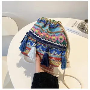 Détail d'un sac seau bohème avec des motifs tissés colorés et des pompons décoratifs