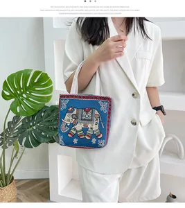 Borsa tote in tela con ricamo etnico a forma di elefante blu tenuta da una modella