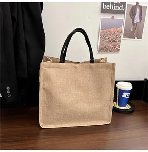 Detail of natural burlap tote bag with round black woven handles on dark wooden desk