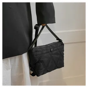 Detail of black quilted dumpling bag with Forever Young strap and nylon fabric texture