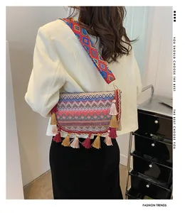 Outdoor shot of bohemian woven crossbody bag with colorful tassels and patterned strap