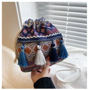 Détails d'un sac seau bohème avec motifs géométriques tissés et pompons décoratifs