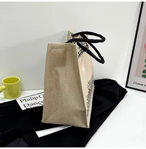 Detailed side view of linen tote bag with black geometric print and braided handles
