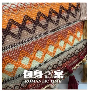 Detail of bohemian woven bag featuring multi-colored geometric embroidery and long tassels