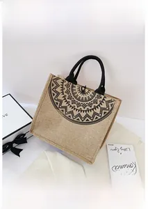 Primer plano del bolso de lino con estampado de mandala negro y asa tejida sobre blanco