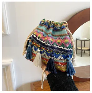 Détail d'un sac seau bohème avec motifs brodés colorés et pompons à franges tendance