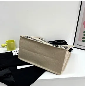 Detail of linen tote bag with geometric pattern trim and black rope handle on a desk