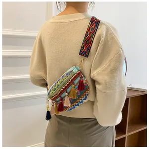 Close-up of ethnic lace crossbody bag with colorful tassels and embroidered strap