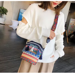 Dettaglio borsa a secchiello boho con ricami etnici, nappe blu e tracolla a fantasia