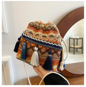 Détail du sac seau tissé bohème avec pompons colorés et fermeture à cordon en coton
