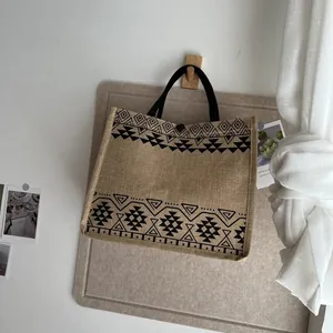 Close-up of ethnic patterned jute tote bag hanging on wooden hook in a minimal interior