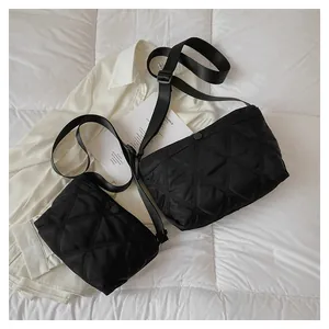Close-up of black quilted nylon bag set with adjustable straps on white fabric
