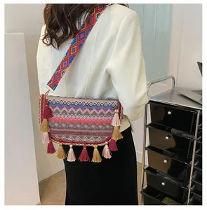 Detailed shot of ethnic woven crossbody bag featuring colorful tassels and wide strap