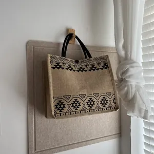 Close-up of linen tote bag with black geometric ethnic patterns on a wooden hook