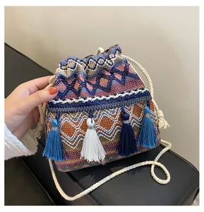 Détail d'un sac seau bohème à cordon avec motifs tissés colorés et pompons bleus
