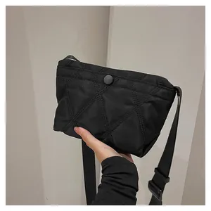 Macro shot of black quilted nylon texture and round buckle on a casual crossbody bag