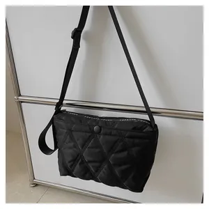 Detail of black quilted shoulder bag with white Forever Young text and snap closure
