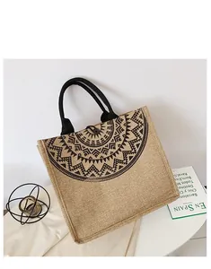 Detalle de bolso tote de lino con estampado étnico negro, asas tejidas y cierre de botón
