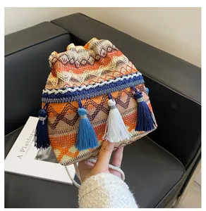 Détail du sac seau tissé avec pompons bohèmes et poignée en corde à cordon