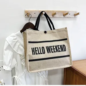 Detail of jute tote bag with black rope handles and Hello Weekend printed slogan