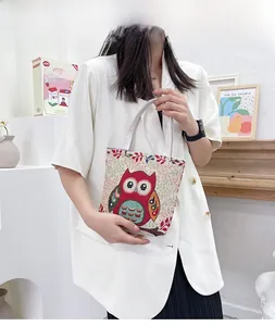 Dettaglio del ricamo a forma di gufo su borsa in tela abbinata a un blazer bianco
