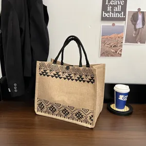 Close-up of ethnic geometric pattern on burlap tote bag with black round handle