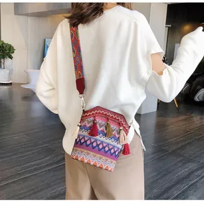 Dettaglio della borsa a secchiello tessuta con motivi colorati e nappe stile boho