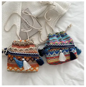 Vue détaillée du sac seau bohème tissé avec motifs géométriques et pompons doux