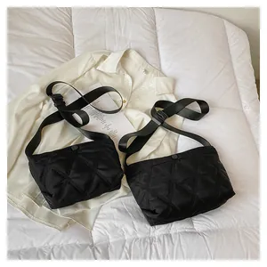 Close-up of black quilted rhombus crossbody bag with adjustable strap and snap closure