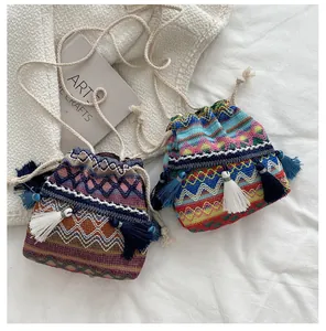 Détail de sacs seaux tissés à cordon avec motifs géométriques colorés et des glands