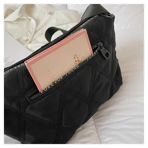 Detail of black quilted crossbody bag showing roomy interior with a pink notebook inside