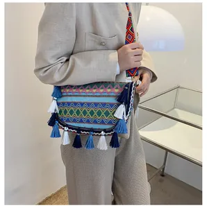 Detail of bohemian woven crossbody bag featuring colorful geometric patterns and blue fringe