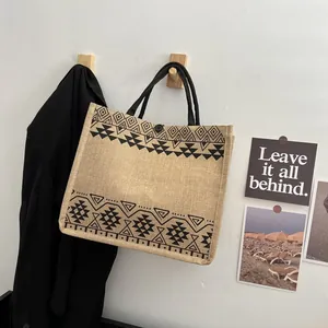 Close-up of ethnic geometric print on jute tote bag with black handles and button closure
