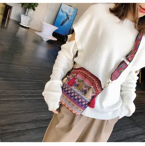 Dettaglio di borsa a tracolla intrecciata con motivi etnici e lunghe nappe su modella