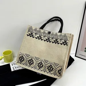 Linen tote bag with black geometric ethnic patterns and a top button closure
