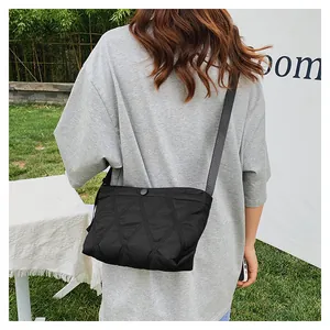 Outdoor shot of a black quilted crossbody bag featuring diamond stitching and a snap closure
