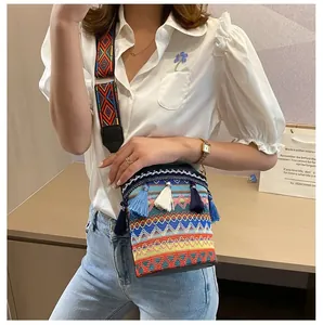 Dettaglio della borsa boho tessuta con motivi etnici geometrici e nappe blu vivaci