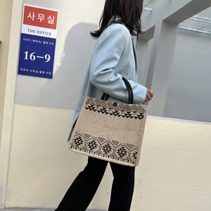 Ethnic style burlap tote bag with black geometric print shown in a street lifestyle view