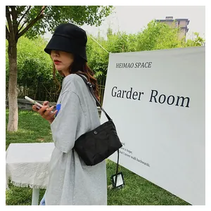 Outdoor shot of a black quilted crossbody bag with adjustable strap and snap closure