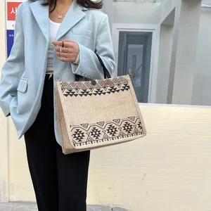 Close-up of beige jute tote bag with black tribal geometric patterns and button closure