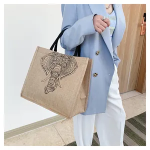 Detail of a large jute tote bag featuring a black mandala elephant print and woven handles