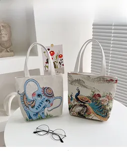Borse in tela con ricamo di elefante cartoon e pavone vintage su un tavolo bianco