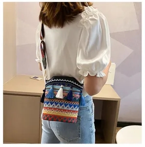 Dettaglio della borsa a secchiello etnica intrecciata con motivi geometrici e nappe
