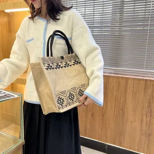 Ethnic jute tote bag with black handles and geometric pattern shown on a model