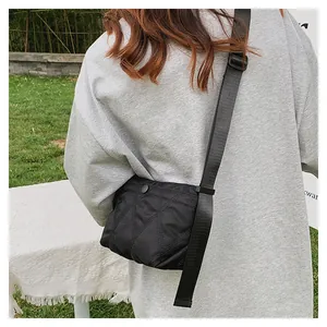 Detail of black quilted crossbody bag with adjustable wide strap and nylon diamond pattern