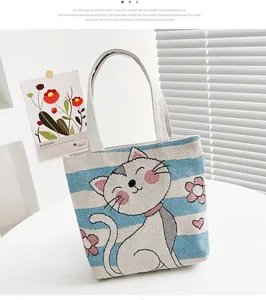Dettaglio borsa in tela con gatto cartoon e strisce blu su un tavolo bianco