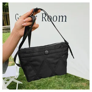 Close-up of black quilted nylon shoulder bag with adjustable strap and snap closure