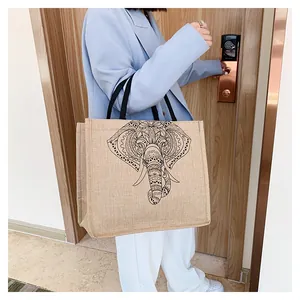 Detail of vintage linen tote bag with elephant print and black rope handles shown on shoulder