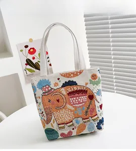Dettaglio del ricamo colorato a elefante su una borsa in lino beige con trama tessuta